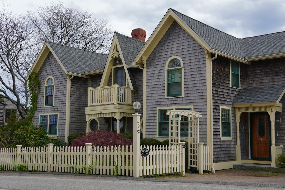 Shingle style house behind a white picket fence